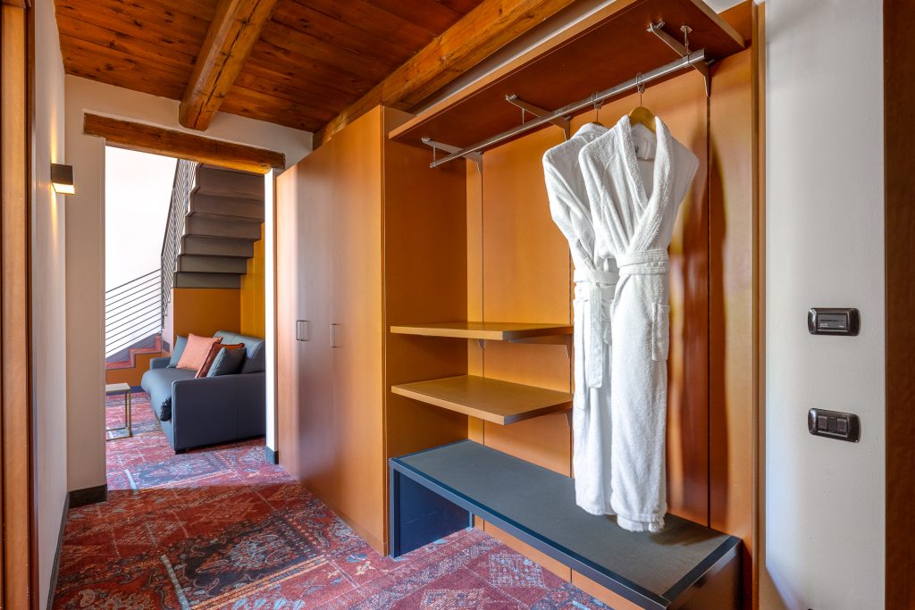 Ingresso suite con accappatoi e travi in legno in un palazzo storico a Venezia: fotografia d'interni per hotel di lusso nel Veneto e in Friuli.